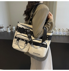 Detail of off-white tote bag with metal rivets, eyelets, and punk-style silver chains