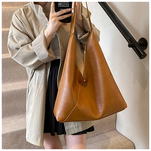 Close-up of caramel faux leather tote bag with lychee texture and wide strap detail