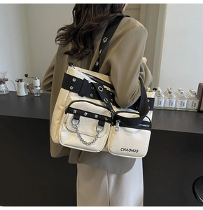 Detail of a functional cream and black tote bag with silver eyelets and metal chains