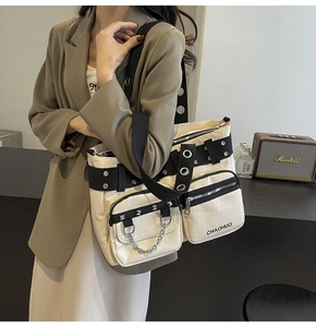Detail of trendy off-white PU leather shoulder bag with punk metal rings and multi-zipper pockets