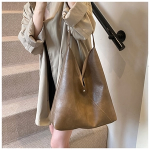 Detail of vintage brown PU leather tote bag showing soft hobo texture on beige trench coat