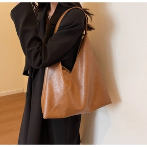 Caramel soft leather tote bag with wide strap worn by model in a minimalist room