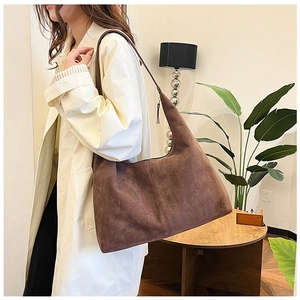 Deep brown matte suede tote bag with wide shoulder strap in a modern minimalist interior