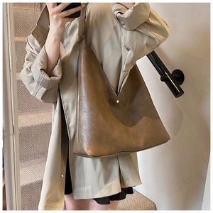 Brown PU leather tote bag worn with a beige trench coat for a minimalist autumn look