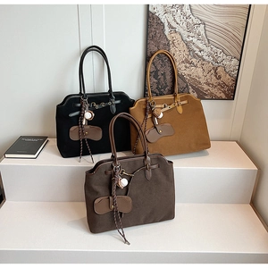 Detailed view of matte suede tote bags in black, brown, and coffee with ball charms