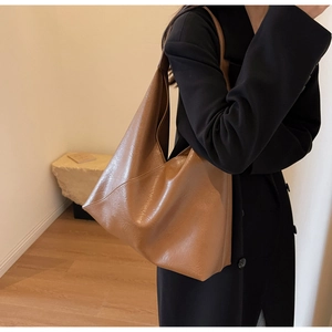 Brown soft leather tote bag with minimalist design shown on model shoulder for daily commute