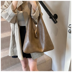 Detail of large dark brown tote bag in glossy leather texture with diagonal stitching