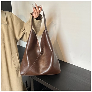 Detailed macro view showing glossy leather texture and seamless stitching of the brown tote bag
