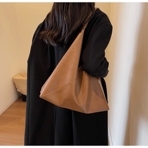 Minimalist brown leather tote bag styled with a modern outfit in a studio setting
