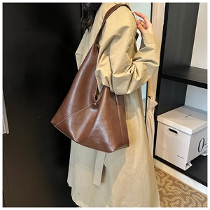 Deep brown PU leather tote bag with wide shoulder strap shown in a daily lifestyle setting