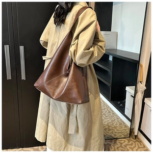 Detail of deep brown vintage PU leather tote bag with glossy texture on a street model
