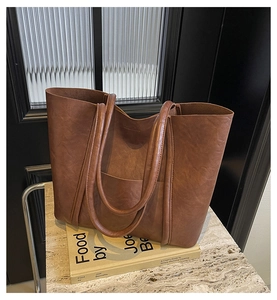 Detail shot of a dark brown PU leather tote bag with fine texture on a marble base