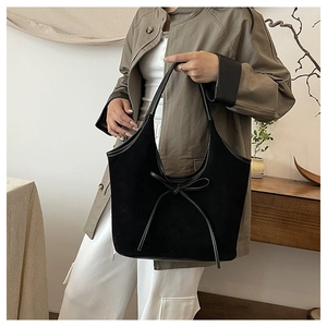 Détail d'un sac cabas noir mat avec nœud en cuir décoratif et longues anses fines