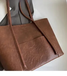 Close-up of vintage brown PU leather tote bag with fine stitching and front pocket detail