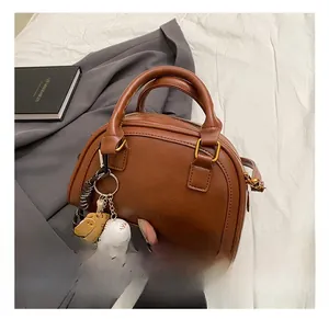 Detailansicht der braunen PU-Ledertasche mit Anhänger und geprägtem Markenlogo-Detail