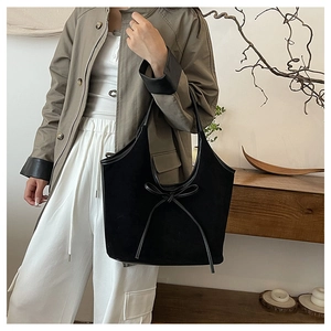 Gros plan d'un cabas en daim noir avec détail de nœud et textures de bandoulière en cuir