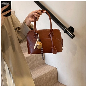 Detail view of brown PU leather handbag featuring white contrast stitching and baseball charms