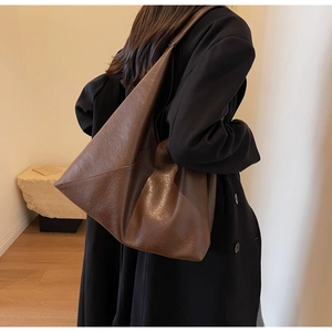 Detailed view of brown faux leather tote bag with unique triangular silhouette and soft texture