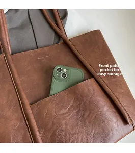 Detail view of brown PU leather tote with front slip pocket for phone storage