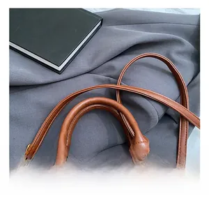 Nahaufnahme der braunen PU-Lederhandtasche mit Rundgriff und goldener Metallschnalle