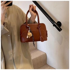 Detail of a brown PU leather shell handbag with white stitching and decorative scarf