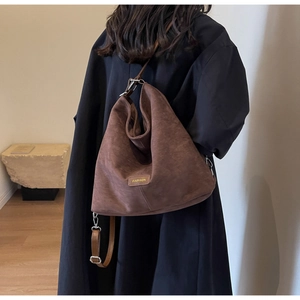 Detail view of a brown matte PU leather shoulder bag featuring a fashion tag and metal hooks