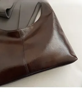 Detail showing the glossy dark brown faux leather texture of a retro hobo bag