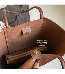 Close-up of brown lychee leather tote bag featuring a magnetic buckle and inner pouch