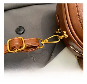 Detailansicht der goldenen Metallhaken und verstellbarem Riemen der braunen PU-Tasche