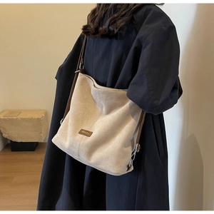 Detail of a beige PU leather tote bag with a brown FASHION tag and slim shoulder strap