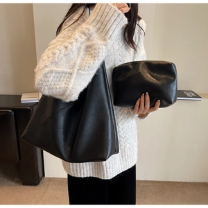 Close-up of black faux leather tote bag and matching clutch showing litchi texture