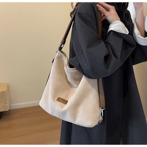 Detail of minimalist beige canvas hobo bag with brown leather straps and fashion label