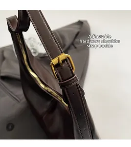 Detail of adjustable bronze metal buckle on dark brown lychee grain faux leather strap