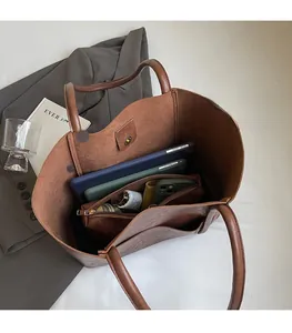 Top view of spacious brown PU leather tote bag interior showing laptop and essentials