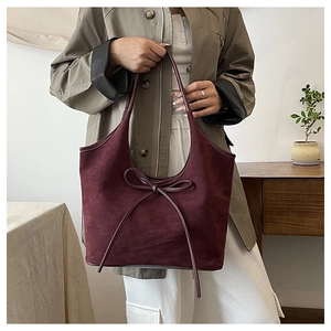 Détail d'un sac cabas en daim bordeaux avec décoration élégante de nœud en cuir