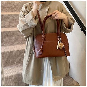 Detail view of brown PU leather shoulder bag with white contrast stitching and heart charm