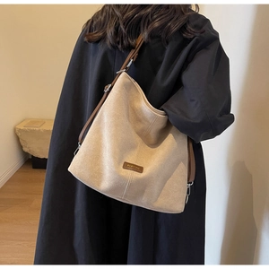 Close-up of a minimalist beige faux suede tote bag with contrast brown leather strap detail
