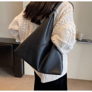 Detailed back view of a large black textured leather tote bag worn over the shoulder