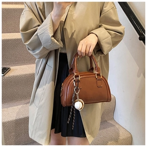 Detail einer braunen PU-Leder Boston Bag mit Baseball-Anhänger und Goldbeschlägen