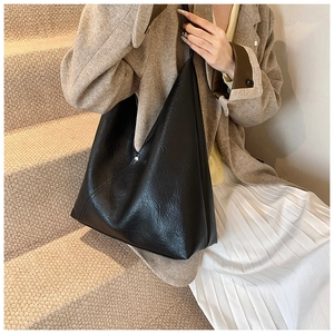 Detail of high-quality black PU leather tote bag with glossy finish and soft pleats