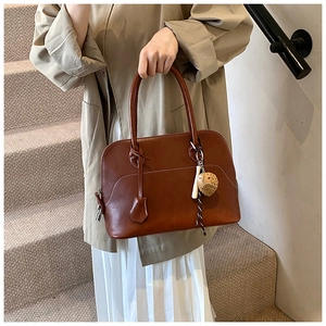 Detail showing smooth brown PU leather shoulder bag with white stitching and owl pendant