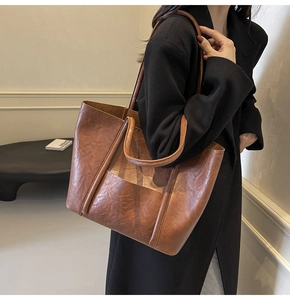 Close-up of vintage brown PU leather tote bag with long double straps on a model's shoulder