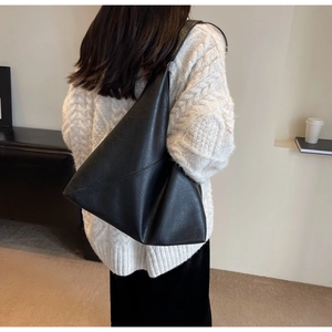Chic black faux leather tote bag with geometric design worn with a white sweater