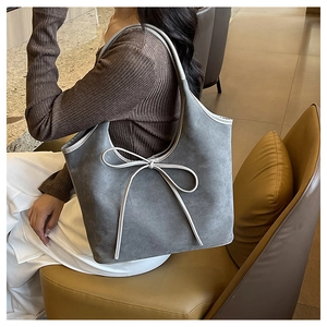 Détail du sac cabas gris mat avec nœud porté à l'épaule dans un intérieur élégant