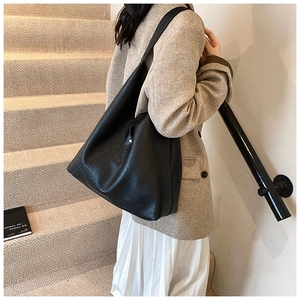 Detail view of stylish black PU leather hobo bag with silver button and textured finish
