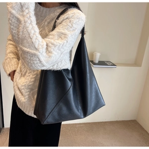Close-up of the pleated faux leather texture and geometric stitching on this black tote bag