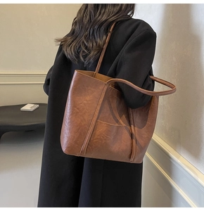 Close-up of brown PU leather tote bag showing vintage texture and front pocket detail