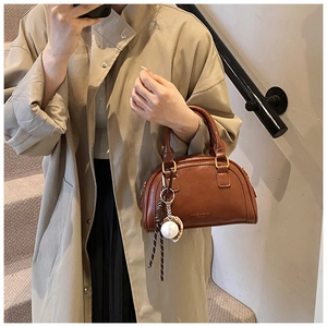 Detail der braunen PU-Leder Bowler Tasche mit runden Griffen und Baseball-Anhänger