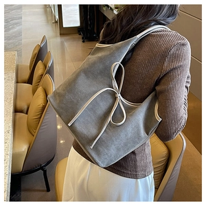 Gros plan d'un sac cabas gris avec un détail de nœud élégant et une texture mate et douce