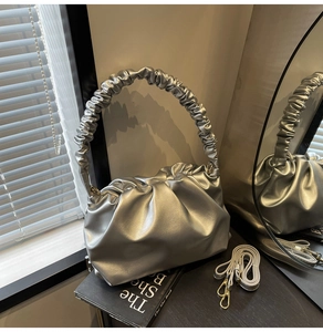 Detailed close-up of the silver pleated cloud bag featuring soft texture and extra strap